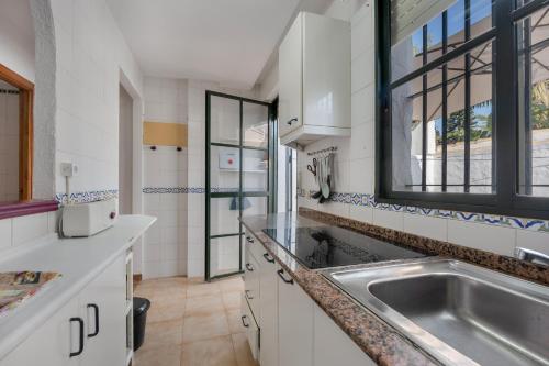 a white kitchen with a sink and a window at Apto Unifamiliar Dos Dormitorios in Chiclana de la Frontera