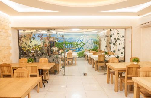 a dining room with tables and a mural at Hoshen Hotel in Umanʼ