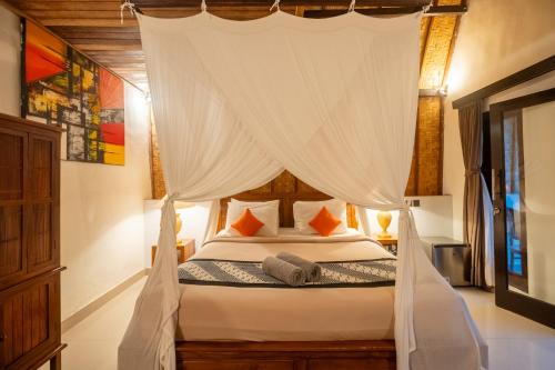 a bedroom with a canopy bed with white curtains at Bintang Bungalow in Nusa Penida