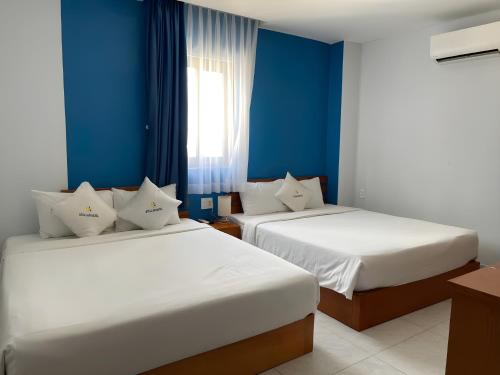 two beds in a room with blue walls at Stellar Phú Quốc - Hotel in Phu Quoc