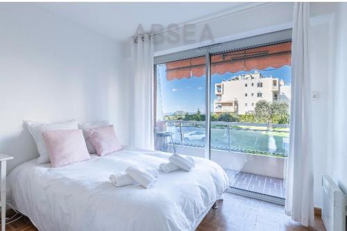 Cette chambre comprend un lit blanc et une grande fenêtre. dans l'établissement Bells terres Nice grand appartement vue mer et jardin,piscine, à Nice