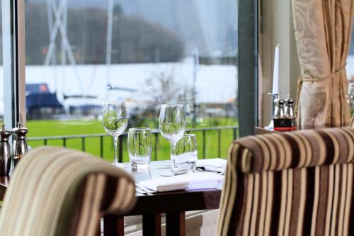 a table with wine glasses on it with a window at Macdonald Old England Hotel & Spa in Bowness-on-Windermere