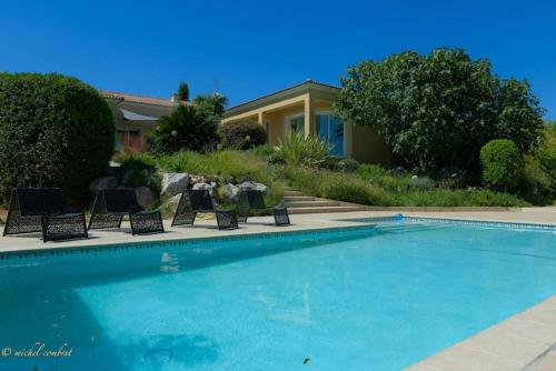 une piscine avec des chaises et une maison dans l'établissement Superbe propriété, piscine, salle de jeux, appareils de sport, à Saint-Aunès