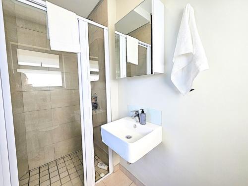 a white bathroom with a sink and a shower at Bella Mare 12 on Second in Gqeberha