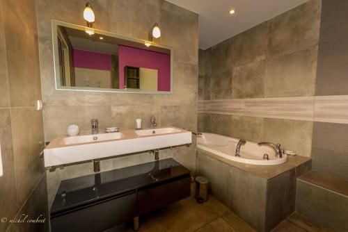 une salle de bain avec deux lavabos, une baignoire et un miroir dans l'établissement Superbe propriété, piscine, salle de jeux, appareils de sport, à Saint-Aunès
