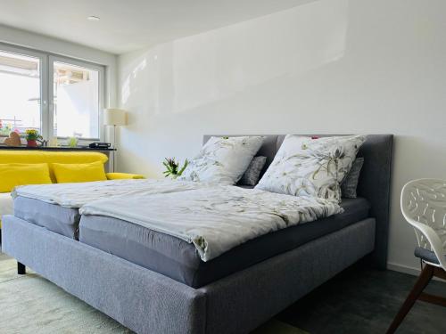 a bedroom with a bed and a yellow couch at Fewo Saur in Immenstaad am Bodensee