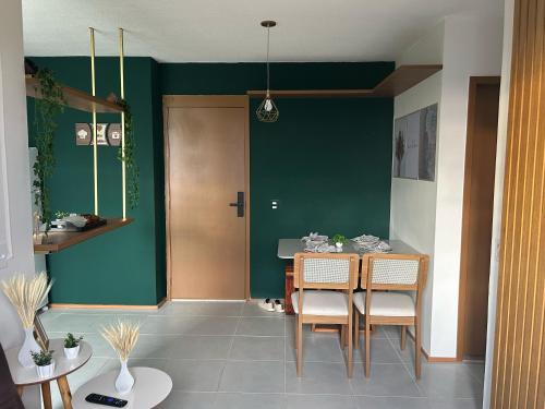 a dining room with green walls and a table and chairs at Vida Mar 14 andar com vista incrível do por do sol in Goiânia