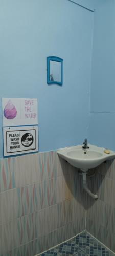 a bathroom with a sink and a sign on the wall at Carpe Diem Guest House in Ko Chang