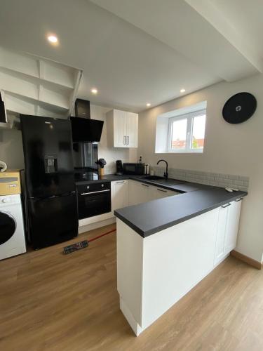 une cuisine avec des armoires blanches et un réfrigérateur noir dans l'établissement Gîte Gravelines, à Gravelines