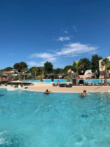 2 personnes dans l'eau dans une piscine à côté d'une plage dans l'établissement Camping Siblu les Sables du Midi, à Valras-Plage