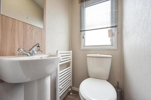 a bathroom with a sink and a toilet and a window at Hope View - Ashbourne Heights Holiday Park in Fenny Bentley