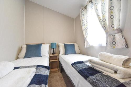 two beds in a small room with a window at Hope View - Ashbourne Heights Holiday Park in Fenny Bentley