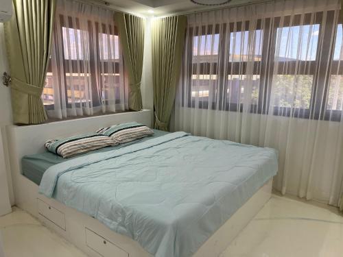 a bedroom with a bed and windows with curtains at Aloha - Your Stylish City Escape in Gate