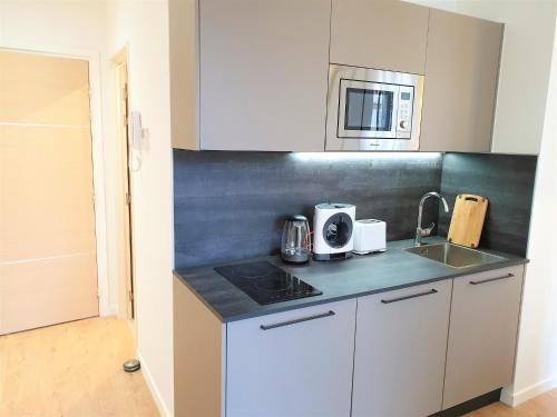 une cuisine avec des armoires blanches, un évier et un micro-ondes dans l'établissement Hypercentre lamartine 411, à Nice