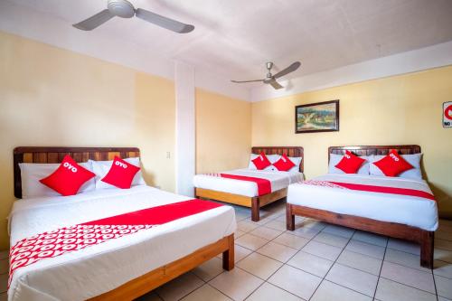 two beds in a room with red and white pillows at OYO Hotel Betsua Vista Hermosa, Huatulco in Santa Cruz Huatulco