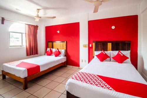 two beds in a room with red walls at OYO Hotel Betsua Vista Hermosa, Huatulco in Santa Cruz Huatulco