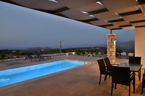 a house with a swimming pool and a table and chairs at Sternes Tropicana Executive Villa with pool, by Comfortbnb in Sitia