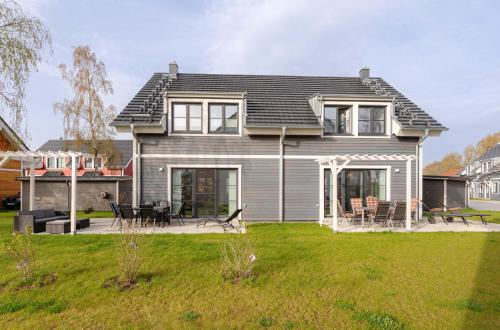 a gray house with a patio and a yard at 5 Sterne Ferienhaus Ostseetraum - 50m zum Strand - Ladestation für E-Auto in Fuhlendorf