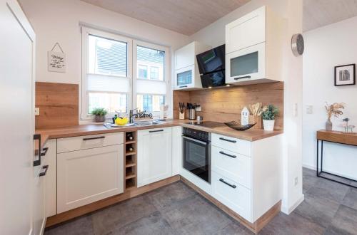 a kitchen with white cabinets and a sink at 5 Sterne Ferienhaus Ostseetraum - 50m zum Strand - Ladestation für E-Auto in Fuhlendorf