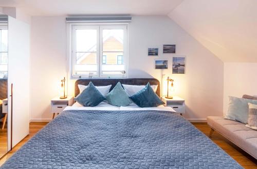 a bedroom with a large bed with blue pillows at 5 Sterne Ferienhaus Ostseetraum - 50m zum Strand - Ladestation für E-Auto in Fuhlendorf