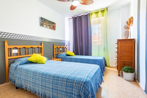 1 dormitorio con 2 camas con sábanas azules y amarillas en Mediterráneo, en Benicàssim