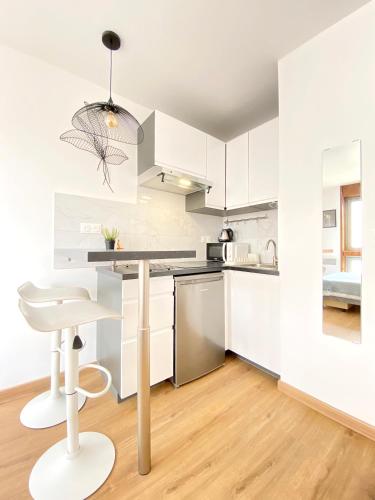 une cuisine avec des placards blancs, une table et un tabouret dans l'établissement Cosy flat walkable distance to Eiffel Tower, à Paris