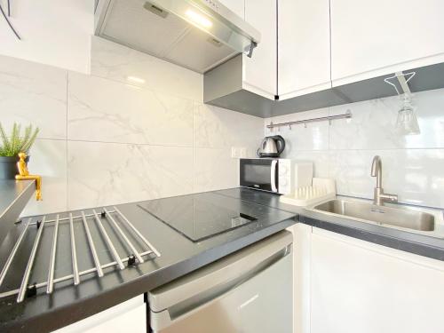 une cuisine blanche avec un évier et un micro-ondes dans l'établissement Cosy flat walkable distance to Eiffel Tower, à Paris