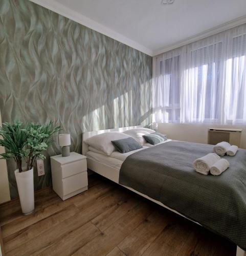 a bedroom with a large bed with towels on it at Central Greatforest Apartman 2 in Debrecen