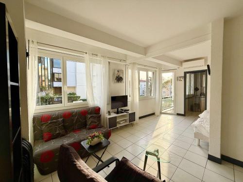 un salon avec un canapé et deux fenêtres dans l'établissement B007 Grand studio lumineux 4 proche centre Cannes, à Cannes