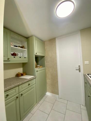 - une cuisine avec des placards verts et un sol blanc dans l'établissement Appartement avec vue sur la vallée de la Dordogne, à Beynac-et-Cazenac