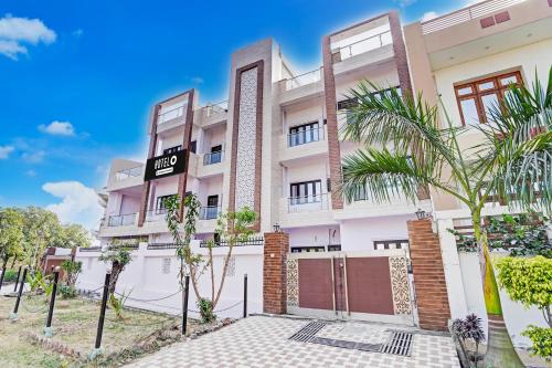 an image of a building with palm trees in front at Super Hotel O Garden View Vrindavan Lucknow in Nilmatha