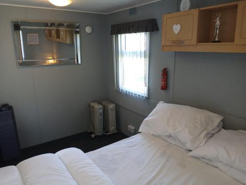 a bedroom with a white bed and a window at Happy Days South Chapel st leonards Sahara 4 Berth in Chapel Saint Leonards
