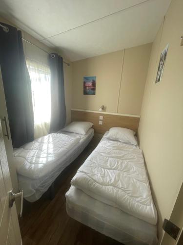 deux lits dans une petite pièce avec une fenêtre dans l'établissement Mobil home au bord de la mer, vue sur la mer camping de la falaise à Equihen-Plage, à Équihen-Plage