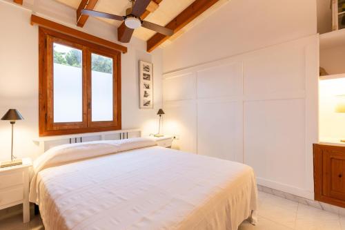 a white bedroom with a bed and a window at Clarona in Cala en Blanes