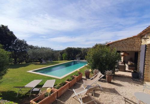 une piscine dans une cour à côté d'une maison dans l'établissement Les Terrasses - Gordes, à Gordes