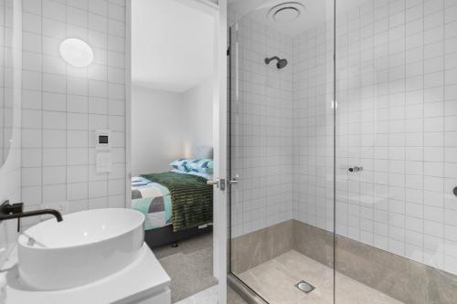 a bathroom with a shower with a toilet and a sink at Heart of Our Garden City in Christchurch