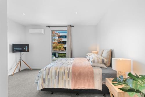 a white bedroom with a bed and a window at Heart of Our Garden City in Christchurch