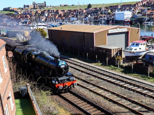 a steam train traveling down the tracks near a marina at Fair Winds in Whitby