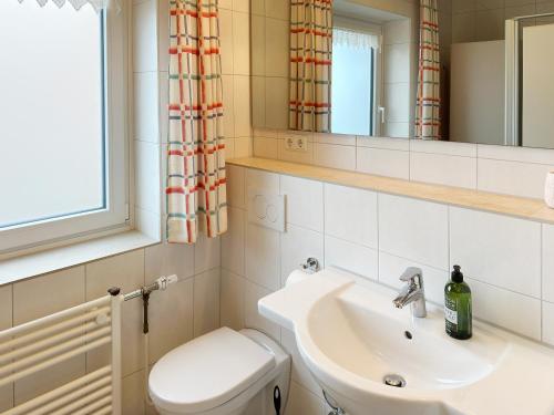 a bathroom with a sink and a toilet and a mirror at Seeanemone Ferienwohnung "Gerding" in Wittdün
