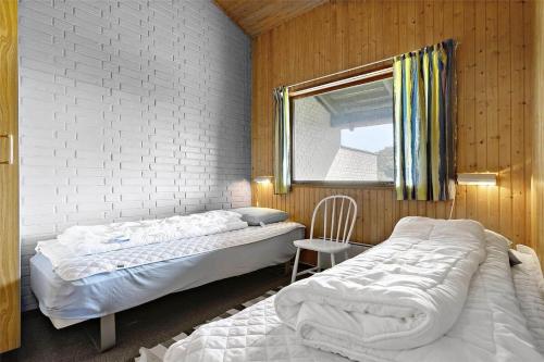 a bedroom with two beds and a window and a chair at Sea view and nature in beautiful Lønstrup in Lønstrup