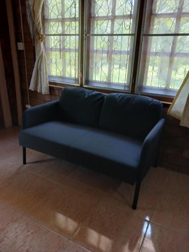 a blue couch sitting in a room with windows at Chompor Homestay in Chiang Dao