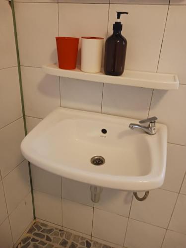 a bathroom sink with two cups on a shelf at Chompor Homestay in Chiang Dao