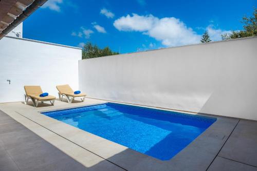 a swimming pool on a patio with two chairs at Sestanyolet in Llucmajor
