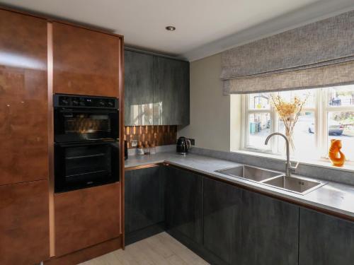 a kitchen with dark wood cabinets and a sink at Fair Winds in Whitby