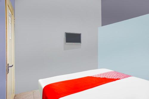 a white bed with a red blanket on it at Hotel O Mandala Near Universitas Negeri Medan UNIMED in Medan