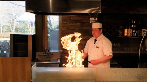 a chef standing in a kitchen with a fire at Hakone Fuga - Adult Only in Hakone