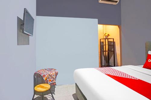 a bedroom with a bed and a chair and a tv at Hotel O Mandala Near Universitas Negeri Medan UNIMED in Medan
