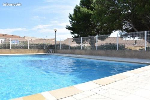 une grande piscine bleue en face d'une clôture dans l'établissement Appartement aux Ayguades à deux pas de la mer, à Gruissan