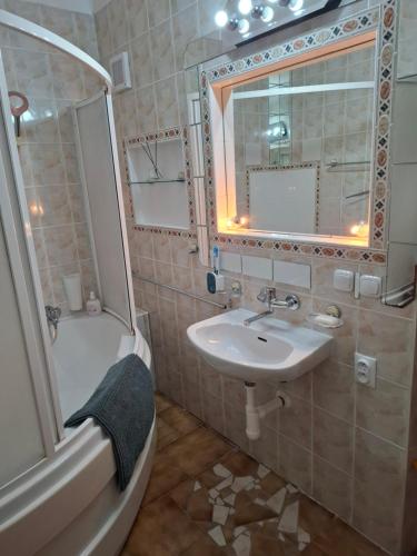 Un baño con lavabo, bañera y espejo. en Byt Kanianka, en Kanianka