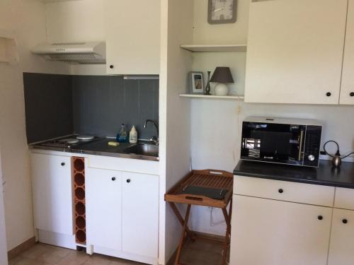 une petite cuisine avec des armoires blanches et un micro-ondes dans l'établissement L'Oasis in Mèze,, à Mèze